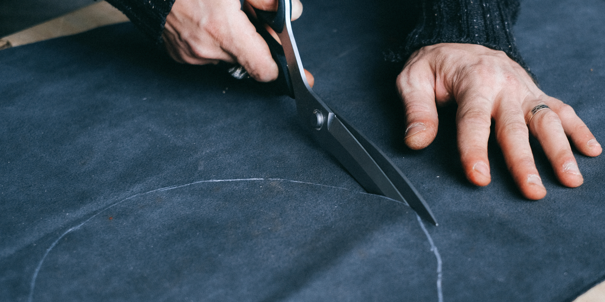 Person cutting blue fabric with KAI scissors